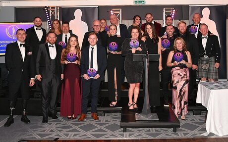 A group of award winners stand in formal attire for a photo