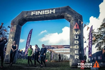 A black, blow up arch with 'finish' written across it. people are walking through the arch dressed in sports wear. 
