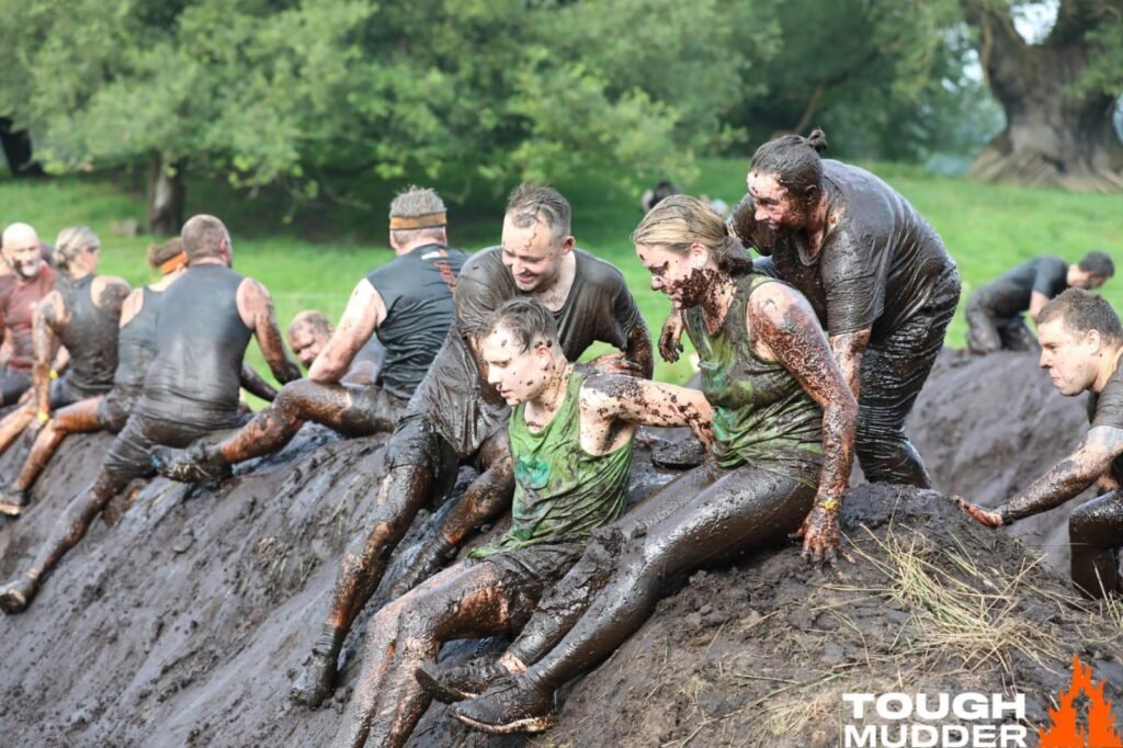 Muddy Tough Mudder participants climb obstacle