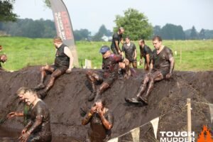 Muddy participants conquer Tough Mudder obstacle