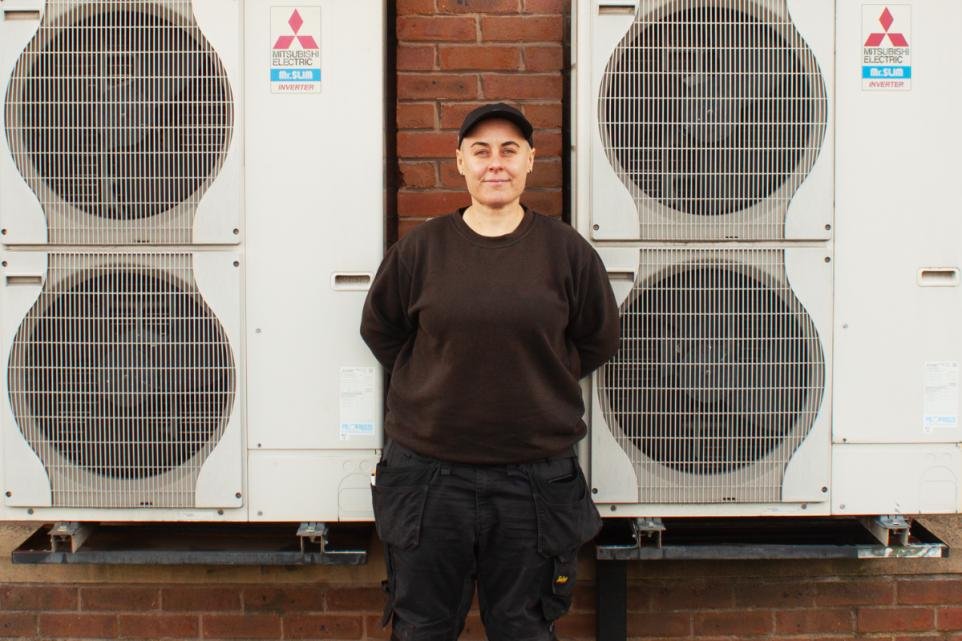Woman in black stands between two industrial air conditioning units