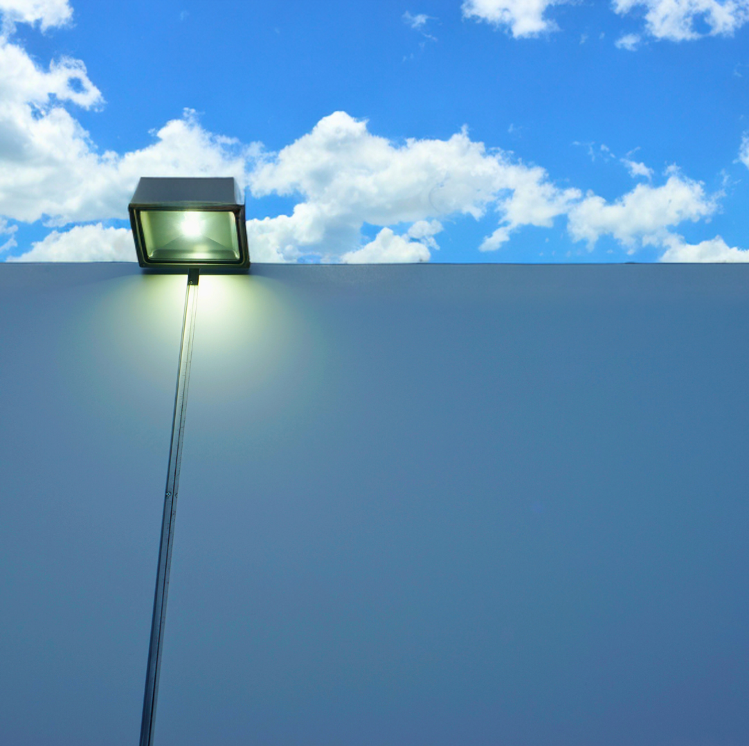 A LED light shining down a blue, metal wall