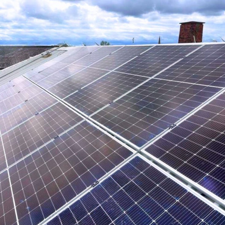 Solar panels on a roof . There are clouds in the sky
