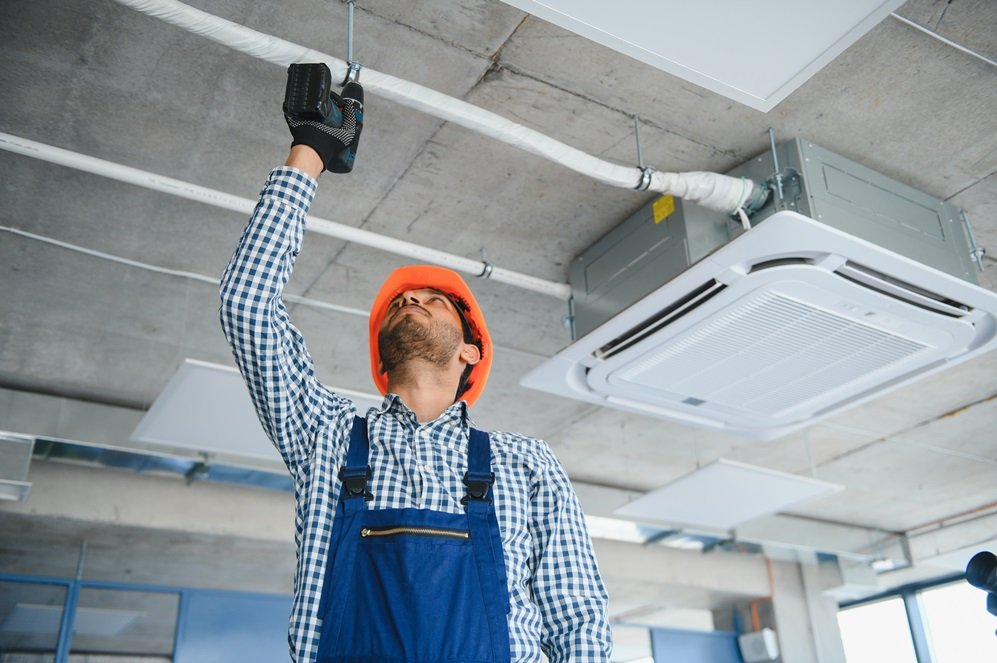 Professional technician maintaining modern air conditioner indoors. Space for text.